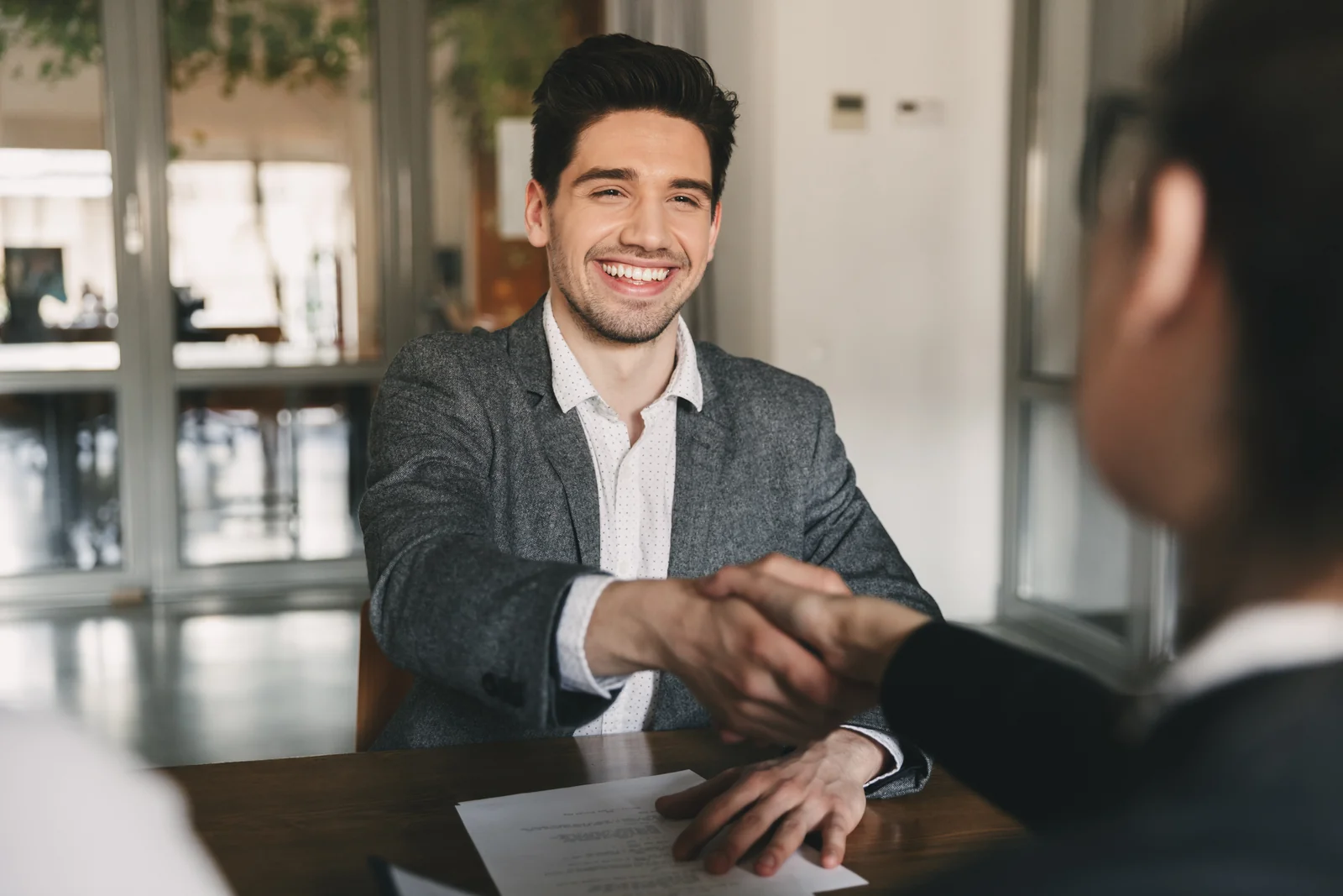 Candidate and interviewer shaking hands across a desk